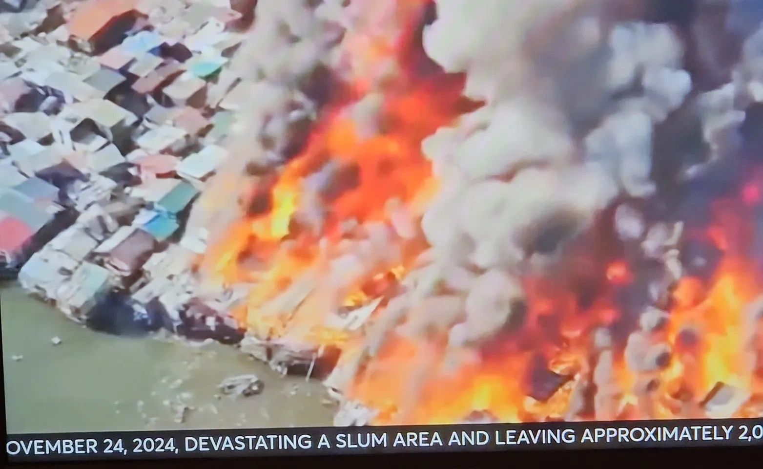 Fire devastates a slum area near water.
