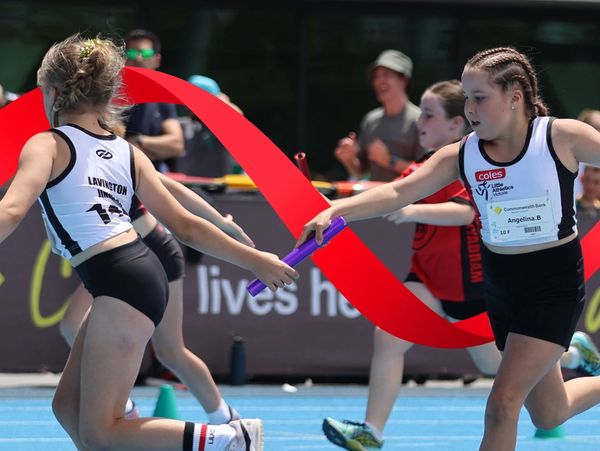 Young athletes passing baton in relay race.