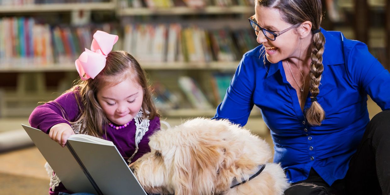 Special needs child with her service dog reading a book
