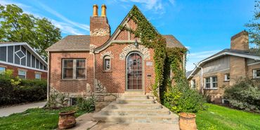 Charming brick house with arched doorway and ivy on the facade.