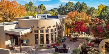 Southwestern style home with autumn trees and outdoor seating area.