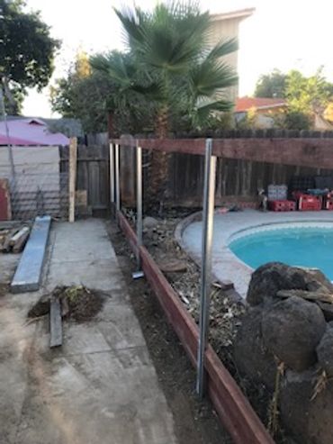 A backyard pool area under construction with metal and wooden framework.