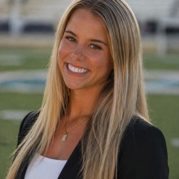 Smiling woman with long blonde hair outdoors.
