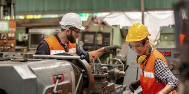 Symbolic photo representing a manufacturing company. Two workers operating machinery