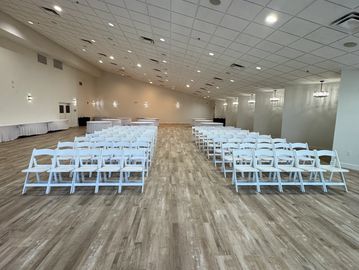 Empty event hall with white chairs.