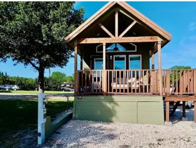 Small wooden cabin with a porch and swing under a clear blue sky.