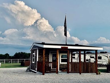 Small wooden cabin with a porch under a cloudy blue sky.