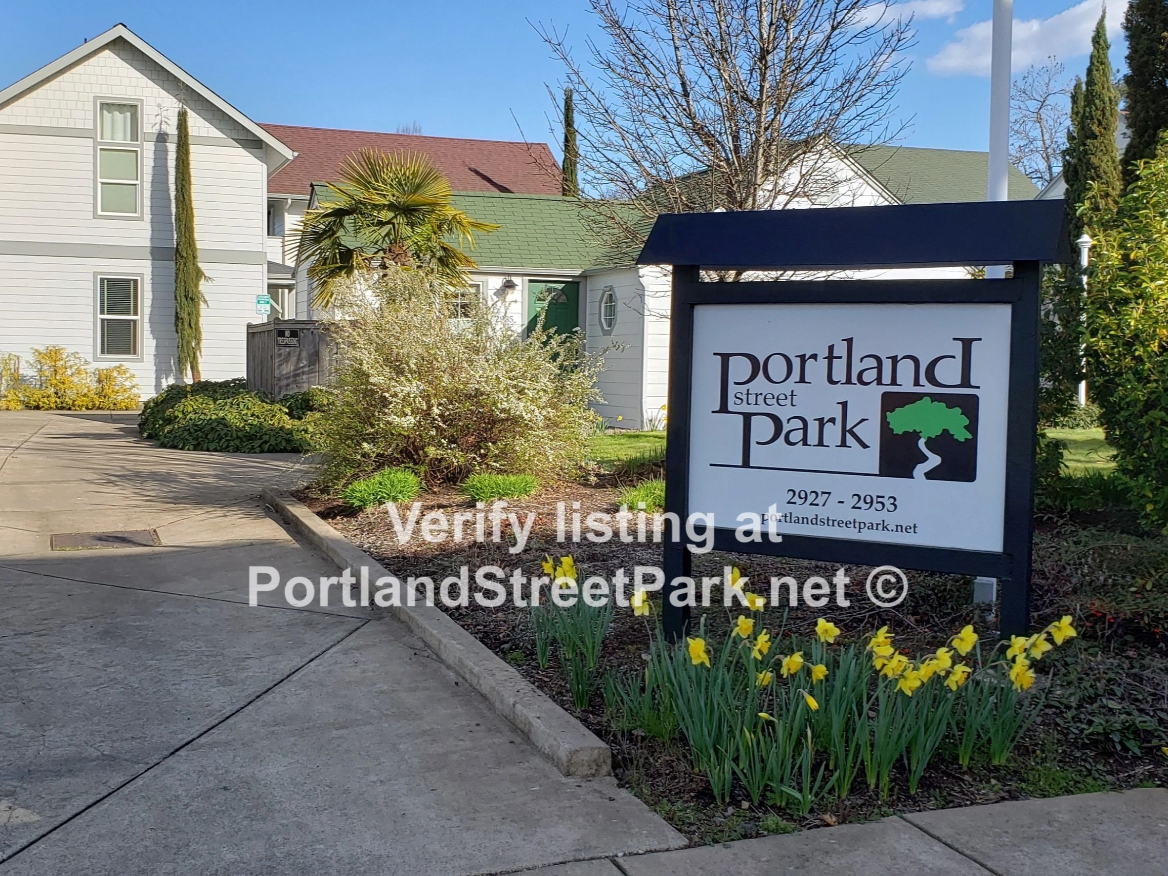 Entrance sign for Portland Street Park with houses and flowers.
