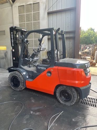 Red and black Toyota forklift parked inside an industrial warehouse.