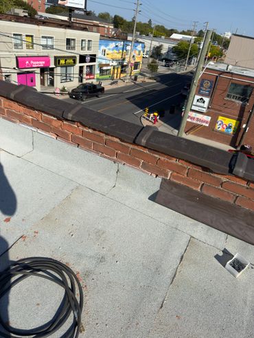 View from a rooftop overlooking a street with shops and a black truck passing by.