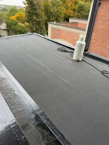 Flat roof with black waterproofing material and a gas tank.