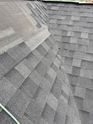 Close-up of a gray shingled roof with layered patterns and nails.