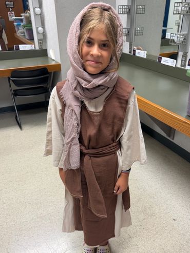 Girl actress in cream tunic, brown overlay, and tan headscarf - Prince of Egypt