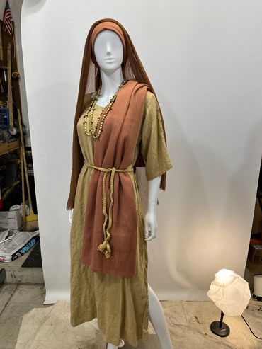 Mannequin dressed in biblical-style outfit with muted earth tones.