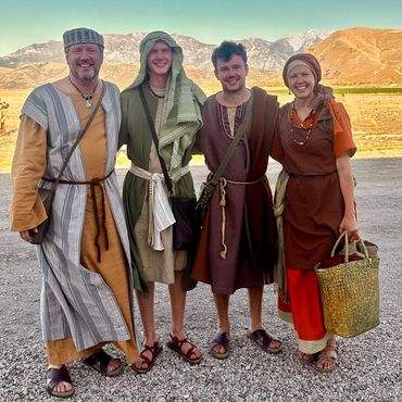 Group of four people in biblical costumes standing in front of mountains