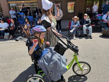 Mother and daughter in Dutch costumes walking and riding bike in parade