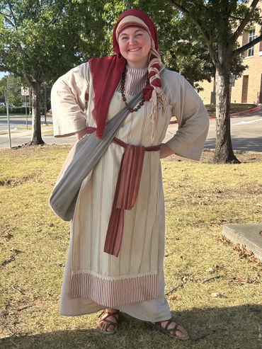 Woman in biblical costume with an big tote bag smiling
