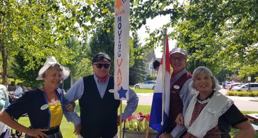 Four adults dressed in Dutch costumes, holding flags