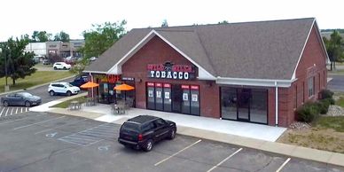 Brick retail store with tobacco sign and outdoor seating.