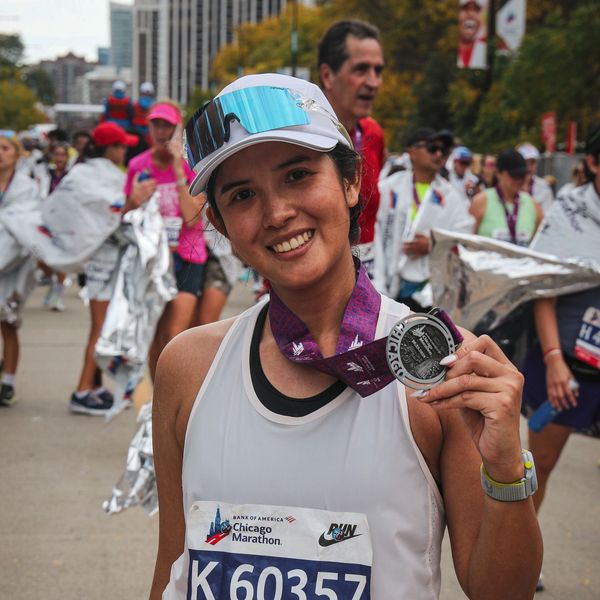 Smiling woman proudly shows her Chicago Marathon finisher medal.