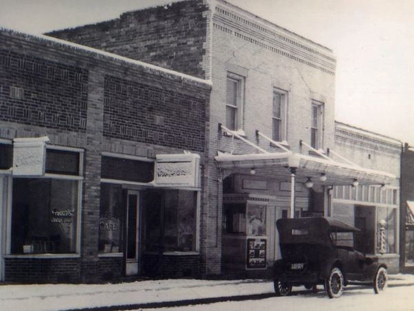 Vintage street scene with old car and brick buildings.