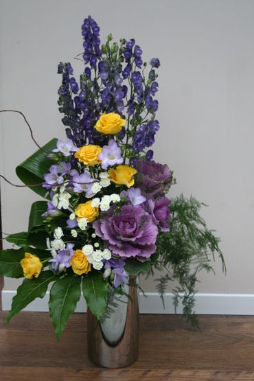 A contemporary flower arrangement on a stand. Suitable as a gift or for a corporate setting.