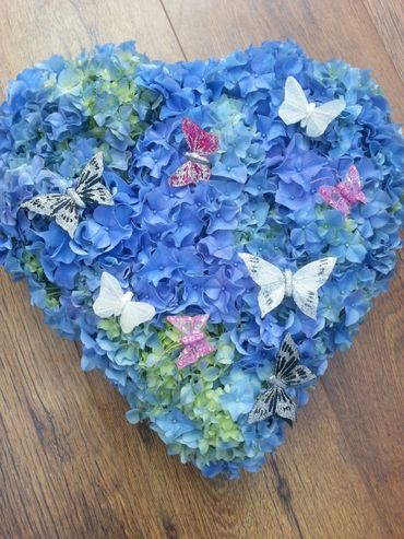 A solid heart filled with blue hydrangea and butterflies