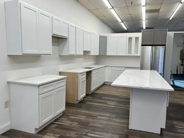 Modern kitchen with white cabinets, marble countertops, and a stainless steel refrigerator.