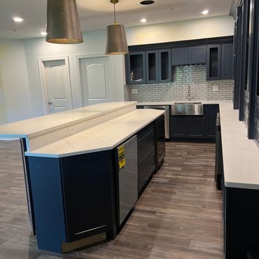 Modern kitchen with navy blue cabinets and white marble countertops.