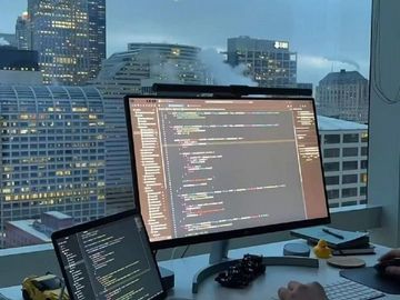 Two screens displaying code with a cityscape background.