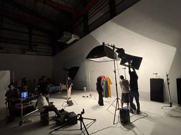 Photography studio setup with lights and crew preparing for a shoot.
