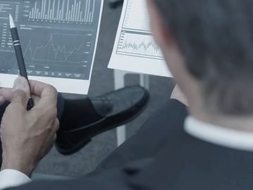 Businessman examining graphs and charts with a pen in hand.