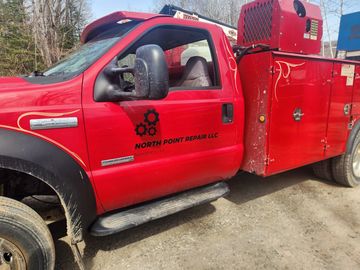 Red repair truck from North Point Repair LLC parked outdoors.