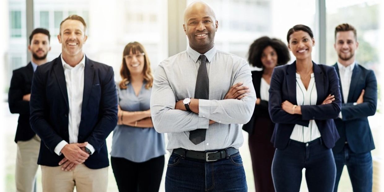 Confident diverse business team standing together in office with smiles.