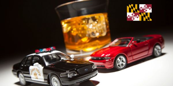 Toy police car and red sports car with whiskey glass and Maryland flag.