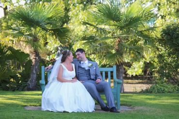 bride + groom sitting on a bench in front of palm trees