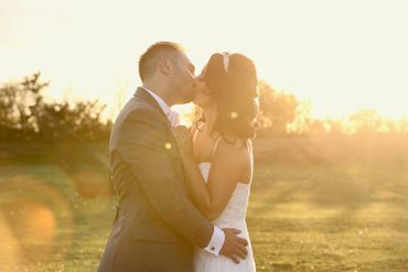 couple kissing with the su behind them