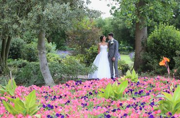 bride and groom looking at each other standing in front of flowerbed