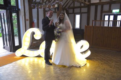 bride and groom in standing in front of love sign