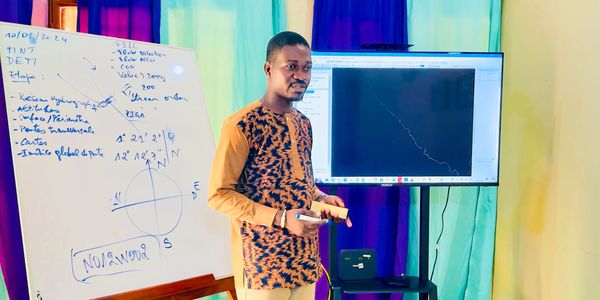Man presenting data with a whiteboard and screen in a colorful room.