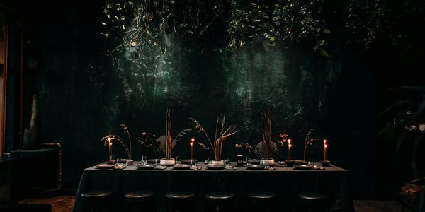 Dimly lit dinner table with candles and elegant dried floral centerpieces.