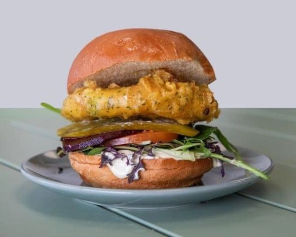 Fried chicken sandwich with fresh vegetables on a plate.