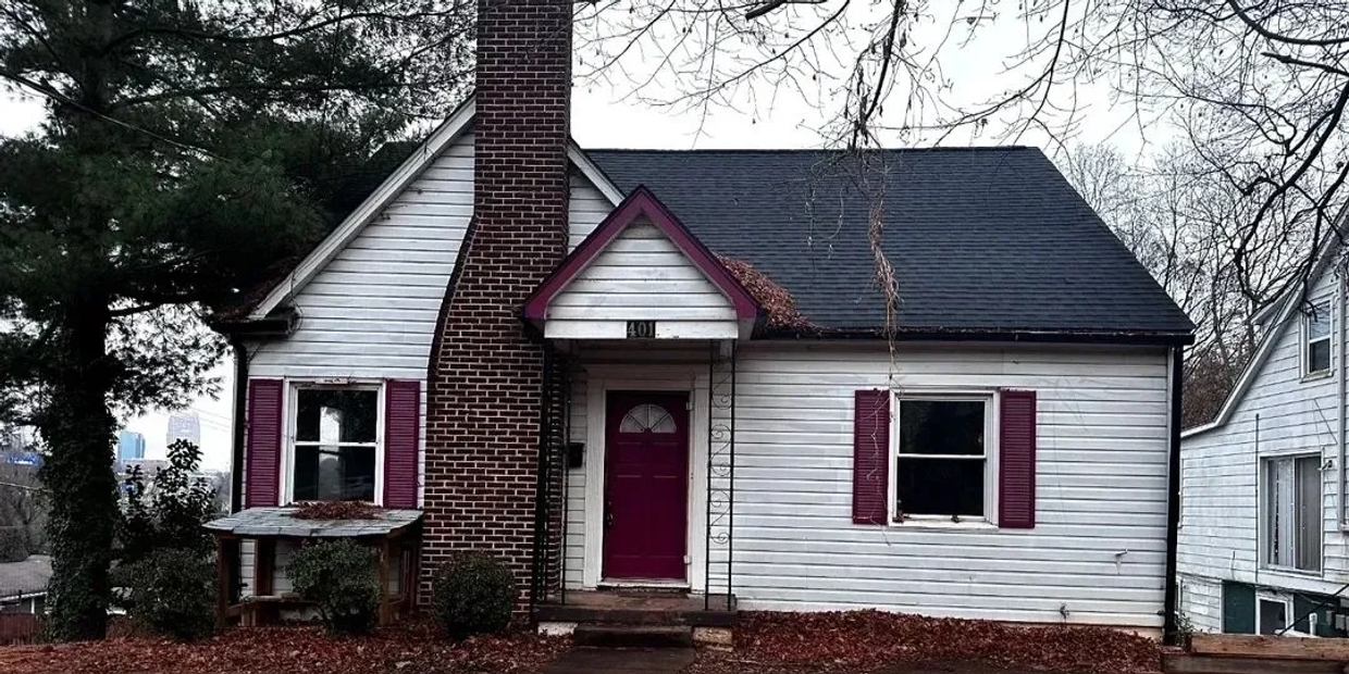 Small house with white siding and purple door and shutters.