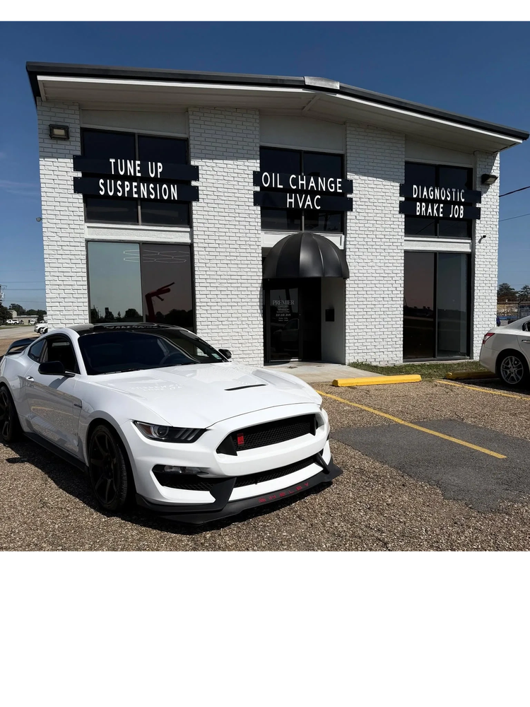 Exterior of a car service center with two white cars parked outside.