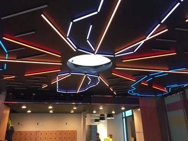 Commercial ceiling with center light fixture and neon lighting radiating out in a sun pattern