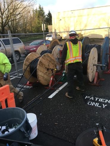 Electrical worker pulling coated electrical wire from large wooden spools