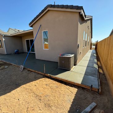 Workers smoothing freshly poured concrete patio at a house.
