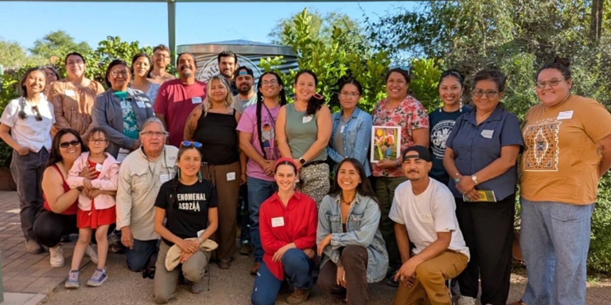 Group photo of diverse adults and children outdoors.