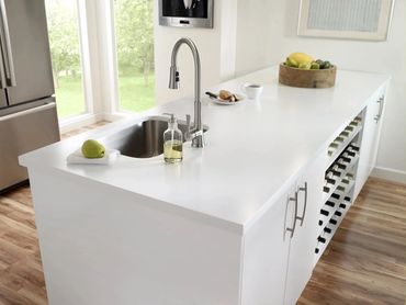Modern white kitchen island with stainless steel sink and fruit bowl.