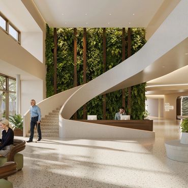 Modern medical center lobby with green wall and spiral staircase.